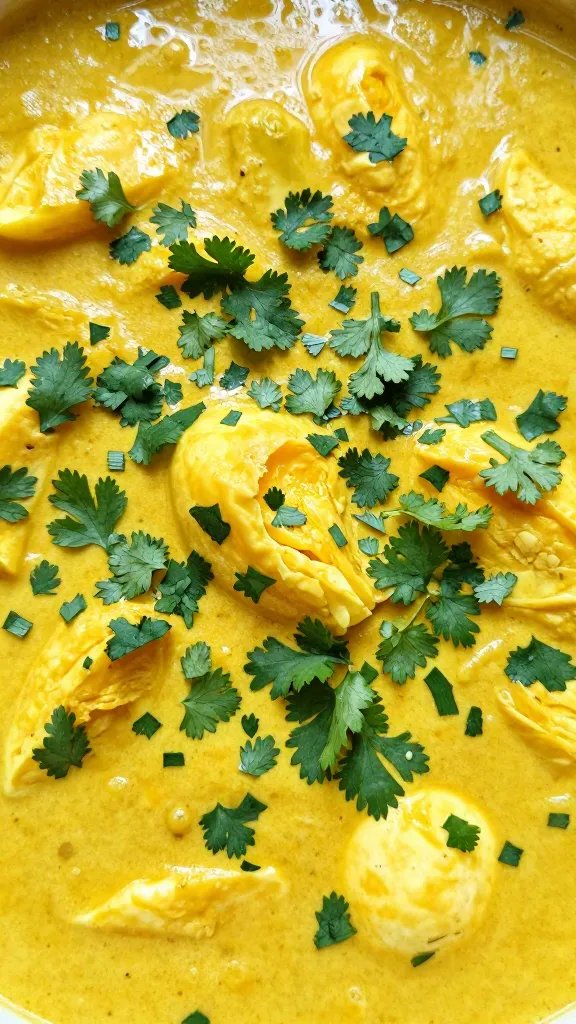 coriander garnish on egg curry surface, tight macro